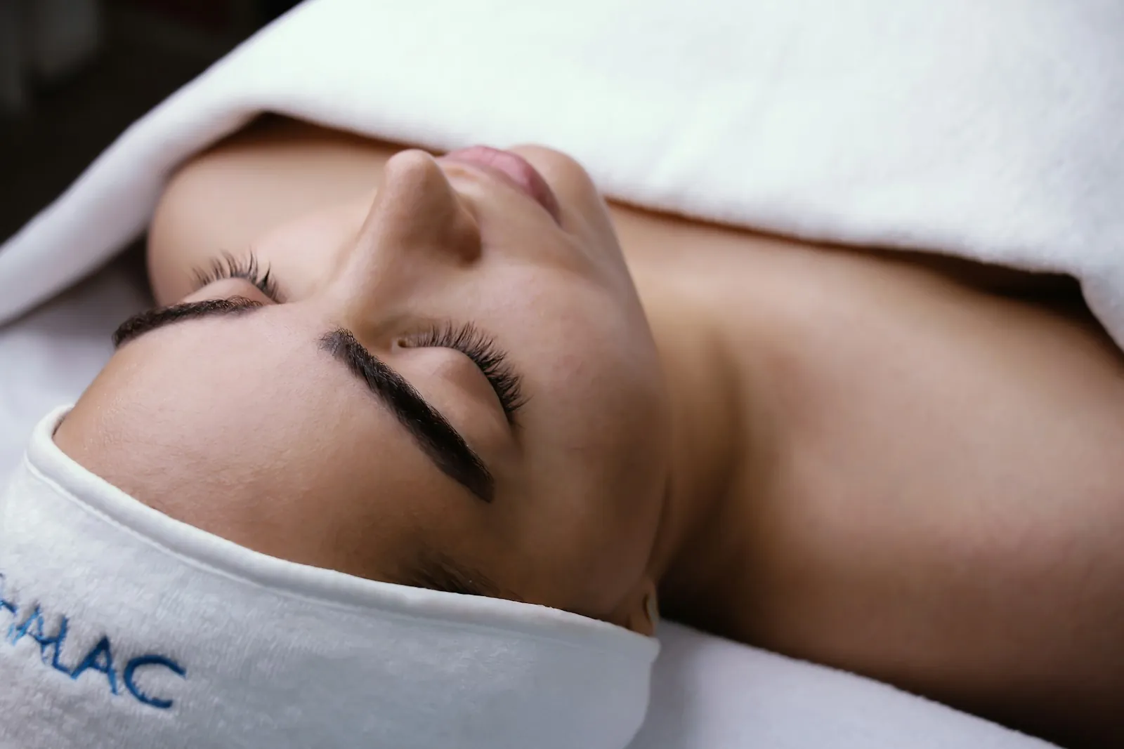 Clienta relajada con los ojos cerrados durante un tratamiento facial